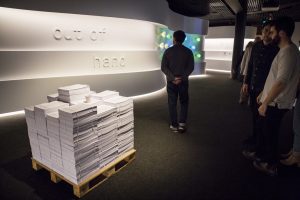 Out of Hand: Materialising the Digital, exhibition opening. People, guests in exhibition. Entrance signage. Who This Am, Kijin Park. (Paper stack) Photo: Jayne Ion. Reproduced courtesy of the Museum of Applied Arts and Sciences.